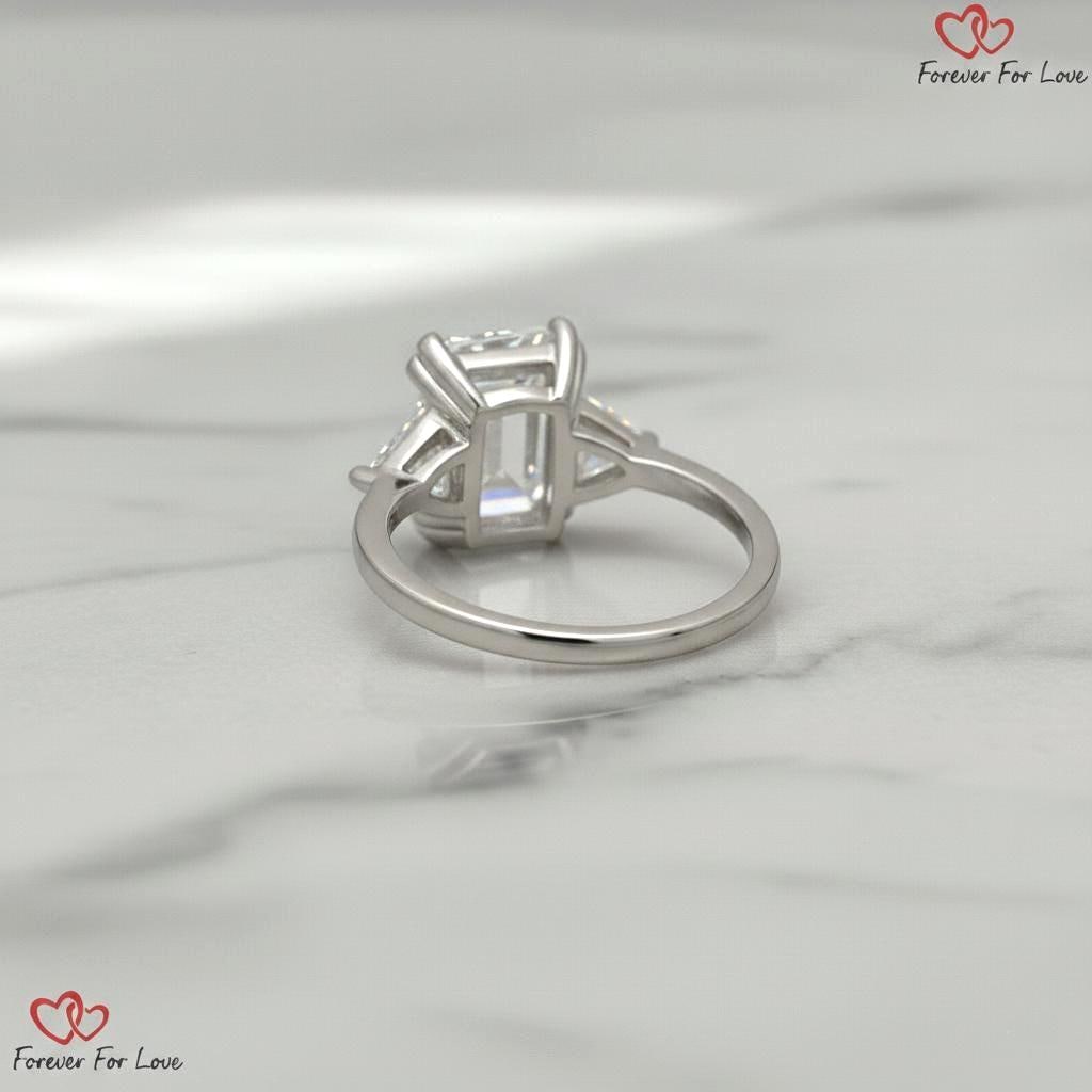 Bague de fiançailles trilogie avec diamants de synthèse taille émeraude 6 carats couleur E pureté VVS2 certifiés IGI et taille trillion sur les côtés, or blanc 18 carats Emerald cut Moissanite engagement ring in Gold or Platinum — custom handcrafted by Forever For Love