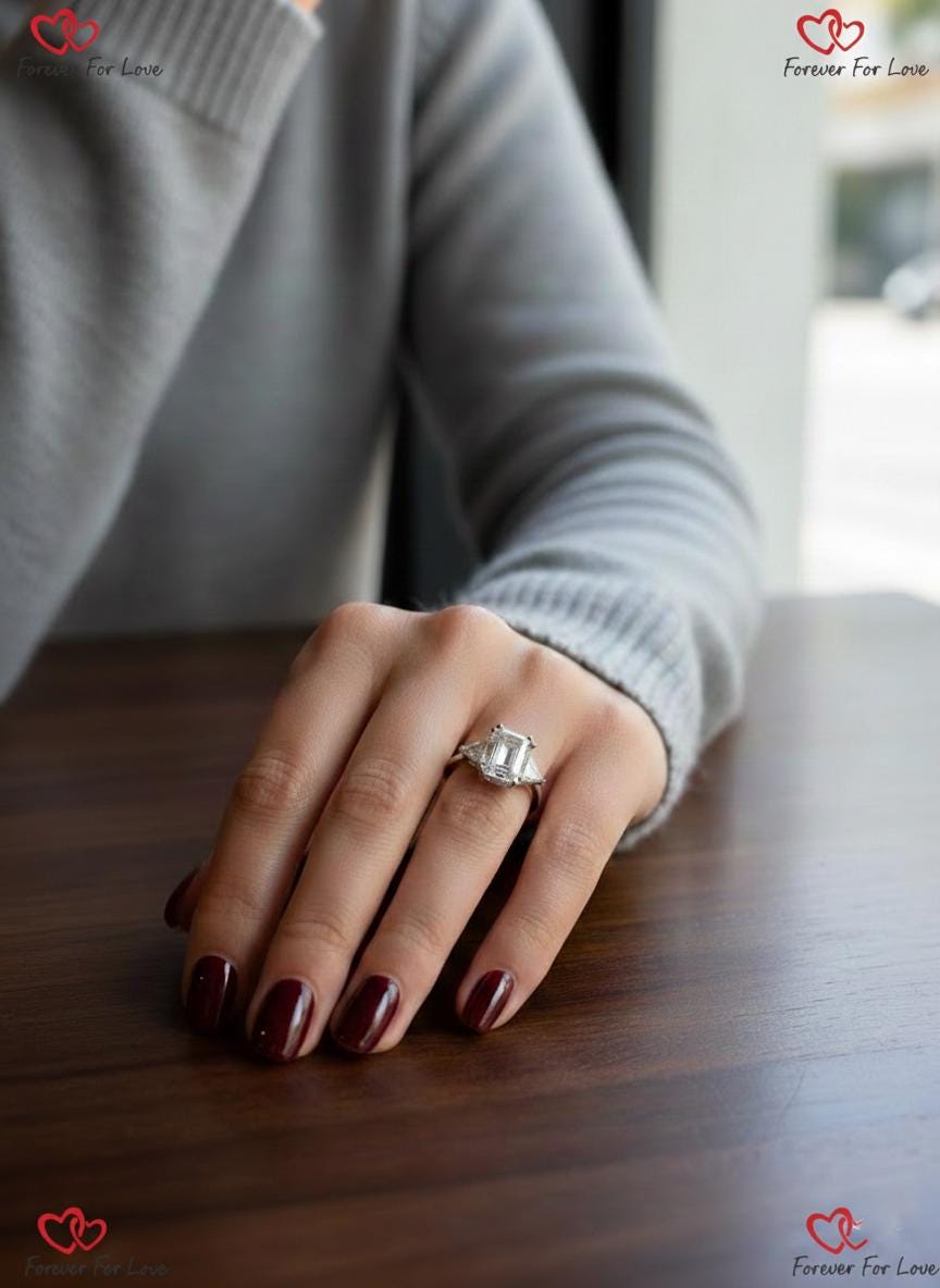 Bague de fiançailles trilogie avec diamants de synthèse taille émeraude 6 carats couleur E pureté VVS2 certifiés IGI et taille trillion sur les côtés, or blanc 18 carats Emerald cut Moissanite engagement ring in Gold or Platinum — custom handcrafted by Forever For Love